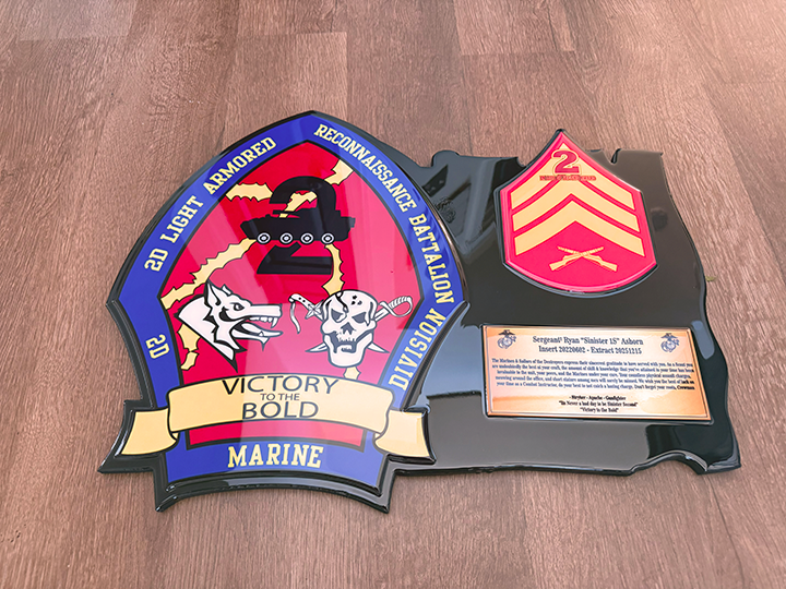 Decorative plaque with military insignia and text on a wooden surface