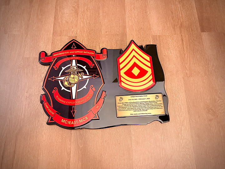 Decorative wall plaque with military insignia and text on a wooden surface