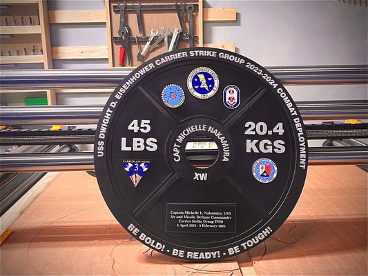A black weight plate plaque with a USMC (United States Marine Corps) logo and text, honoring a service member with a 45 lb weight designation.