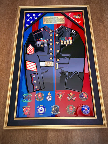 Framed display of a military uniform with various insignias and a flag on a wooden surface.