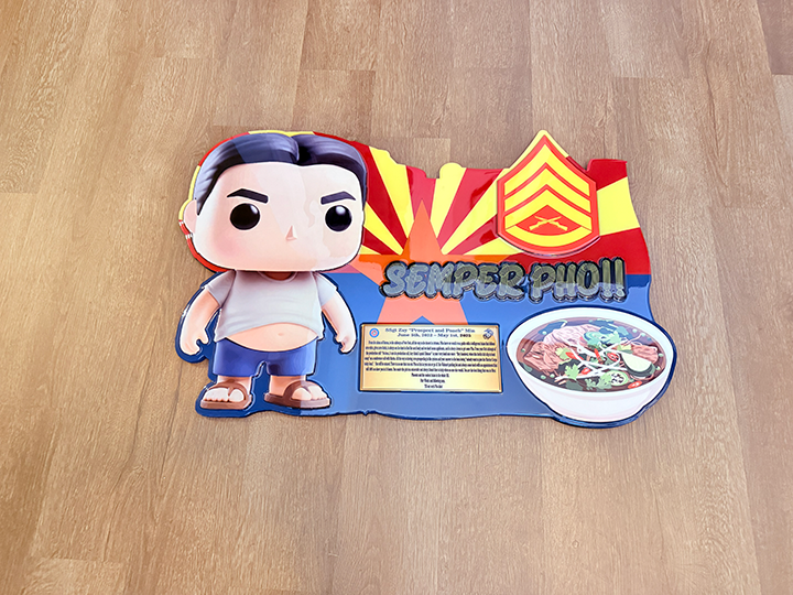 Funko Pop! vinyl figure with a colorful standee displaying 'Semper Fi!' on a wooden surface.